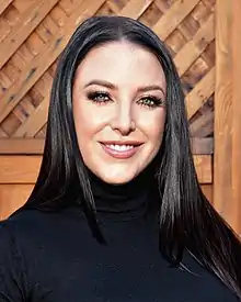 Portrait of a smiling woman with shoulder-length dark hair, wearing a black turtleneck