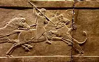 Ashurbanipal on his horse thrusting a spear at a lion’s head
