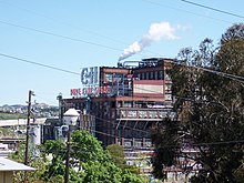 A large industrial building seen through trees.
