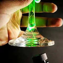 Total internal reflection of a green laser in the stem of a wine glass.