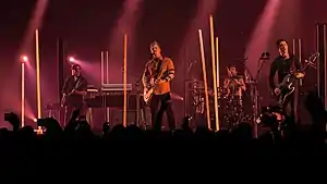 Queens of the Stone Age performing at Wembley Arena in November 2017; left to right: Dean Fertita, Josh Homme, Jon Theodore, and Michael Shuman