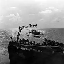 Photo by Horace Bristol of a Curtiss SOC scoutplane being hoisted on board the USS Philadelphia.
