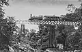 A photo shows an SS300 class steam engine (later type C11) hauled an SS inspection car passing a bridge on the Bangil-Malang railway line