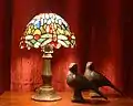 Typical Tiffany copper-foil lamp with dragonfly design, with two pigeon sculptures