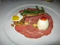 A unique version of steak and eggs with carpaccio beef, quail egg, deviled egg and vegetable salpicon