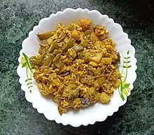 A bowl of moringa flowers cooked in Bengali style chorchori, with hyacinth beans, eggplants, and potatoes