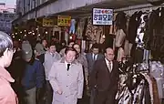 The Mayor of Seoul Yeom Bo-hyeon [ko] (front, black tie) tours the market (1983)