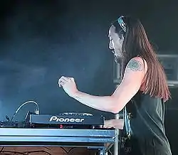 Steve Aoki playing a keyboard while standing against a black backdrop.