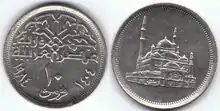  10 Egyptian Piastres ( copper-nickel alloy composition and silver color ), coin’s obverse depicts Muhammad Ali Mosque from a flat perspective, coin reverse contains a Kufic font inscription of “Jumhuriyat Masr Al-Arabia”, translating to the Arab republic of Egypt, below which the denomination of 10 Piastres is written as number hovering over the word “qurush”, translating to piastres, which bends with the curvature of the coins edge, which is surrounded by the Gregorian (1984) and Hijra (1404) dates.