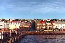 A wharf with warehouses on the left; on the right are two-storey brick houses. Similar two-storey houses line the streets beyond.