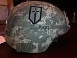 Half scale insignia of the 1st Maneuver Enhancement Brigade worn on the right side of an Advanced Combat Helmet.