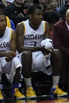 Ingram sitting on the bench of a basketball court next to his teammate