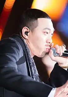 BewhY wearing a dark outfit, appearing to rap into a microphone onstage