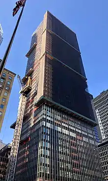 An image of 270 Park Avenue being demolished in 2019. Some windows have been removed, and there is scaffolding around the upper stories, which are being deconstructed.