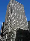 Ground-level view of a rectangular building with a dark gray facade and clear windows