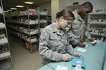 Two people wearing military uniforms counting medication on a counter