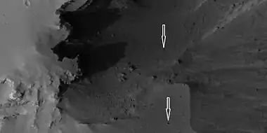 Boulders and their tracks from rolling down a slope, as seen by HiRISE under HiWish program. Arrows show two boulders at the end of their tracks.