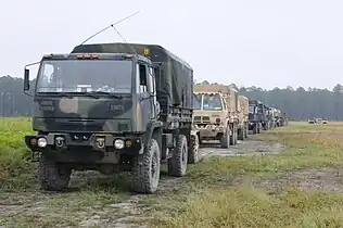 A M1078 A1R (front), with an Oshkosh-produced M1083 A1P2 in A-kit configuration immediately behind