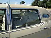 Closeup image of rear roofline of a 1977 Lincoln Continental Town Car, showing padded rear vinyl roof and opera windows