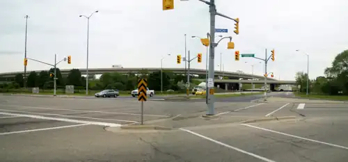 A ground level photo of an intersection, with a series of ramps in the background