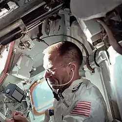 View from side of a white suited astronaught in an orbiting vessel writing with his right hand