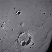 Lunar crater Krieger and vicinity, showing wrinkle ridges in the surrounding mare and sinuous rilles along the left edge, from Apollo 15