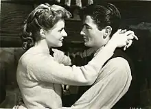 A black and white photograph of a woman, left, and a man, right, hold their arms around each other