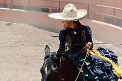 Mexican Escaramuza charra wearing sombrero in a chareada.