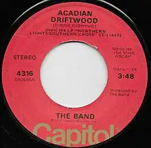 Single label for 'Acadian Driftwood' by the Band. Written by Robbie Robertson, From the LP Northern Lights Southern Cross, on Capitol Records. Performed and produced by The Band. 0:14 intro, track length 3:48. Capitol 4316.