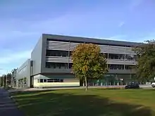 A contemporary building constructed with glass and steel with silver and coloured cladding set in mature landscape