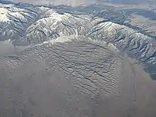 Aerial photo of the Great Sand Dunes partially surrounded by a mountains range with ridges and valleys