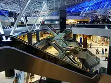 Interior of an airport terminal, with stairs and escalators