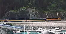 A train and the highway passing a harbor