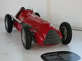 a red vintage open-wheel racing car in a museum