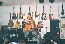 coffeehouse-like concert at place with many guitars on wall