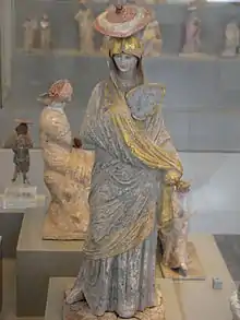 Ancient Greek statue of a lady with blue and gilt garment, a fan and a sun hat, from Tanagra, c. 325–300 BC.