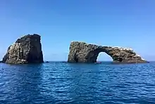 View of Arch Rock with calm ocean in front