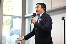 Yang holding a microphone while making a speech.