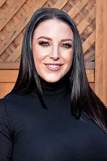 Portrait of a smiling woman with shoulder-length dark hair, wearing a black turtleneck