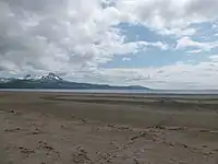 Wide flat beach with snow-capped mountains in the background