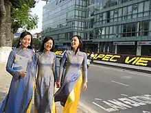 Three girls wearing blue ao dai are leading each other