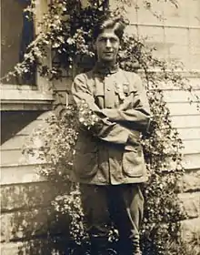 Young man in a 1910 era Boy Scout uniform displaying the merit badges on his sleeve