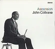 In a black-and-white photo, Coltrane sits on a stool facing right, wearing a three-piece suit and holding his saxophone between his legs. To the right, the word "stereo" appears in the upper corner in black, with "Ascension" written in multiple colors beneath it, followed by "John Coltrane" in black below that.