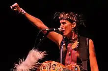 Andrea Echeverri playing guitar onstage, punching the air with her fist