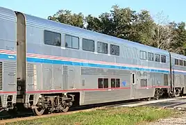 Stainless steel bilevel passenger rail cars with a blue stripe and two thinner red stripes between levels, plus a red sill stripe