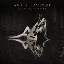 Avril Lavigne sitting nude in a pool of water holding an acoustic guitar close to her body.