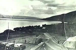 Group of tents and motor cars with Sea of Galilee in background