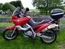  Red BMW F650ST with topbox parked on grass in front of a rustic wooden fence