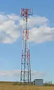 A BTS tower. The antenna is on top and the shelter housing the BTS on the right