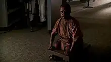 A man who is missing his legs rests on a wheeled cart.